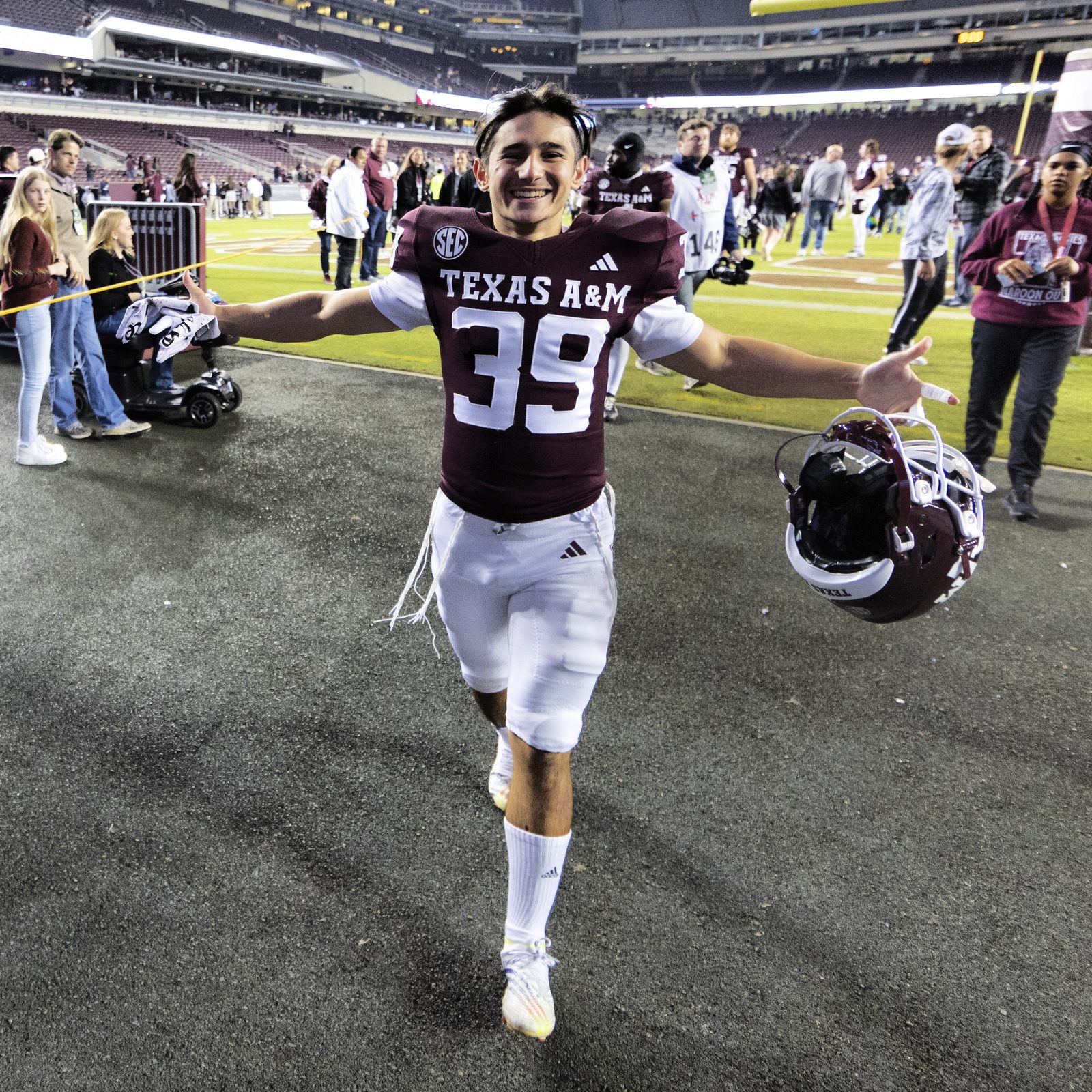 Sam Salz celebrating as he comes off the field, arms outstretched, helmet in hand.